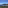 Clear blue bay, green forested hills, rocky coastline, and coastal buildings.