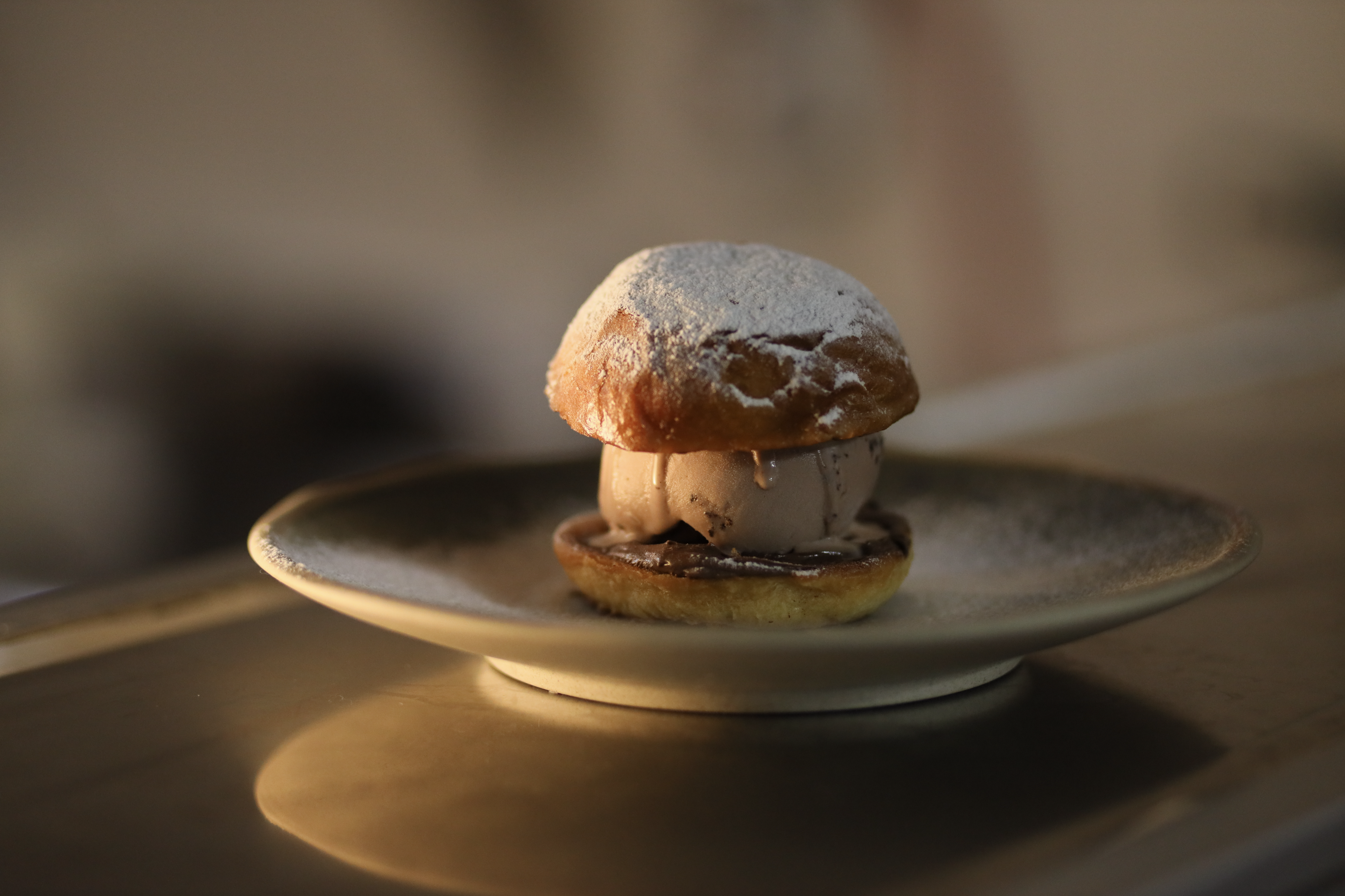 Gourmet chocolate ice cream brioche sandwich dusted with powdered sugar.