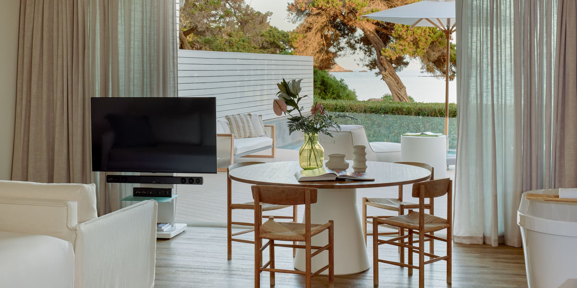 Open-plan living room with dining, TV, and stunning sea view patio.