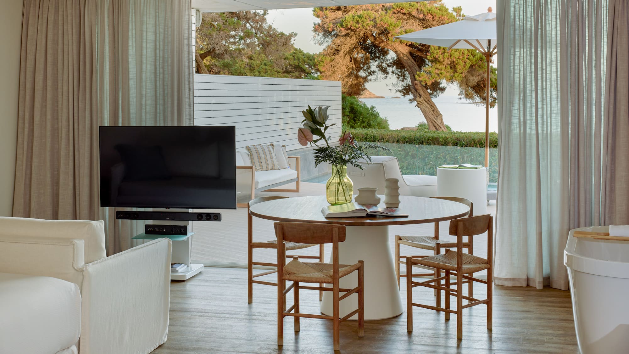 Open-plan living room with dining, TV, and stunning sea view patio.