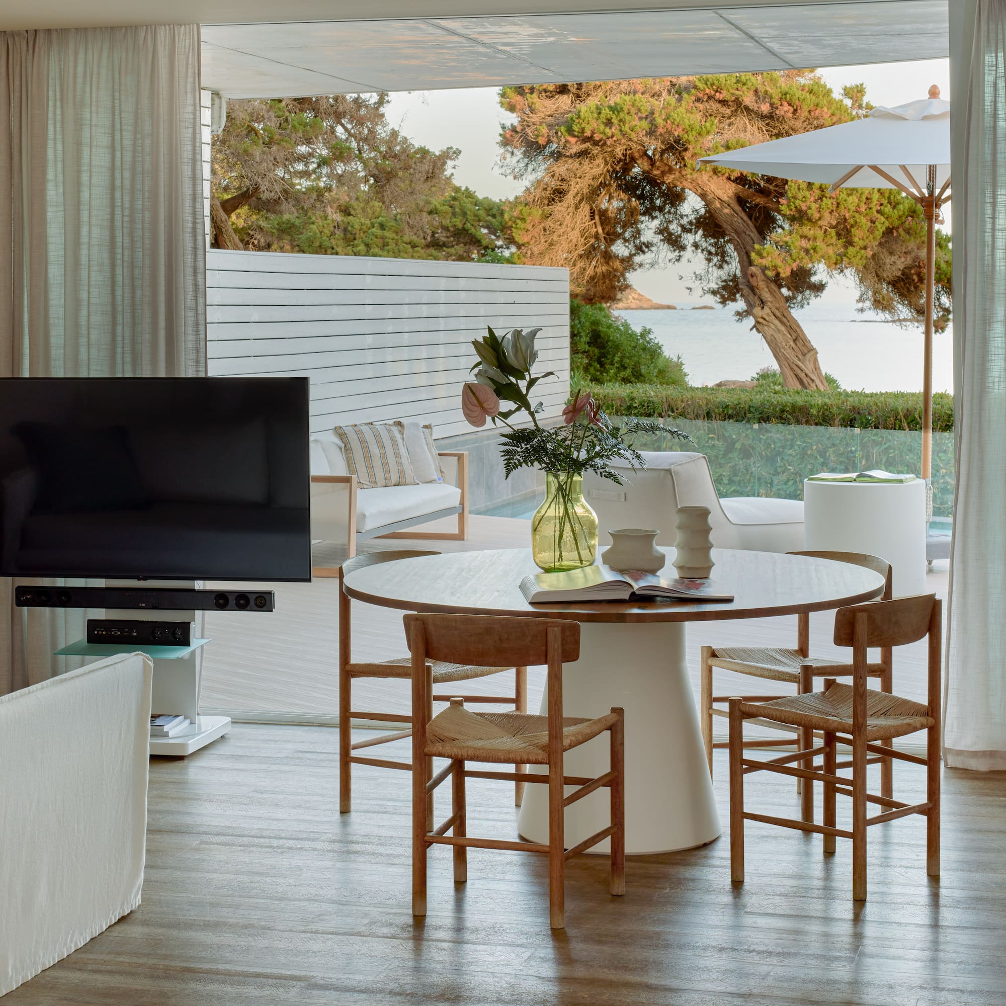 Open-plan living room with dining, TV, and stunning sea view patio.