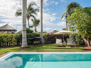a pool with chairs and umbrellas in the back