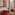 Contemporary hotel room, red chairs, patterned headboard art, city view.