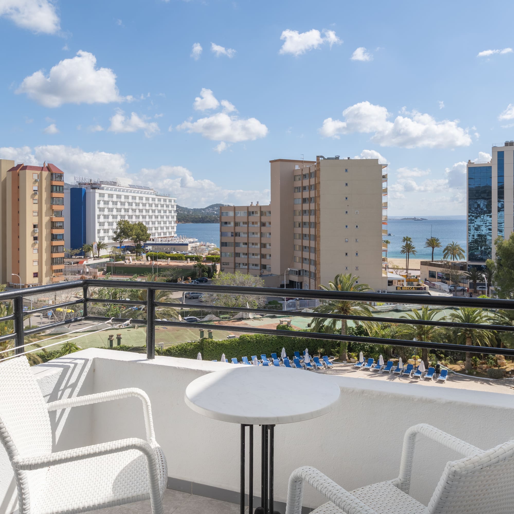 a balcony with chairs and a table overlooking a body of water