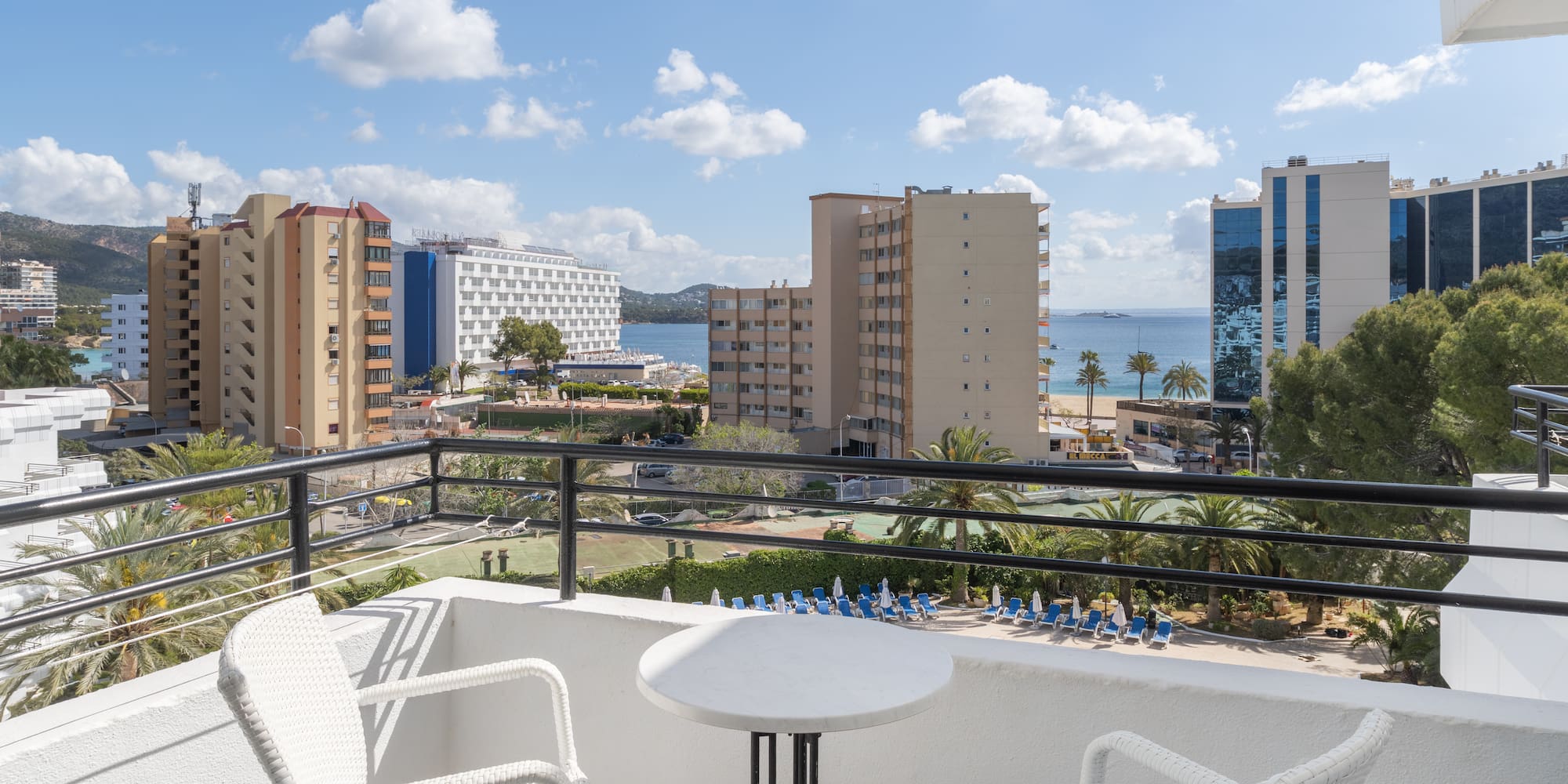 a balcony with chairs and a table overlooking a body of water