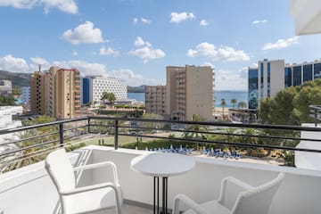 a balcony with chairs and a table overlooking a body of water