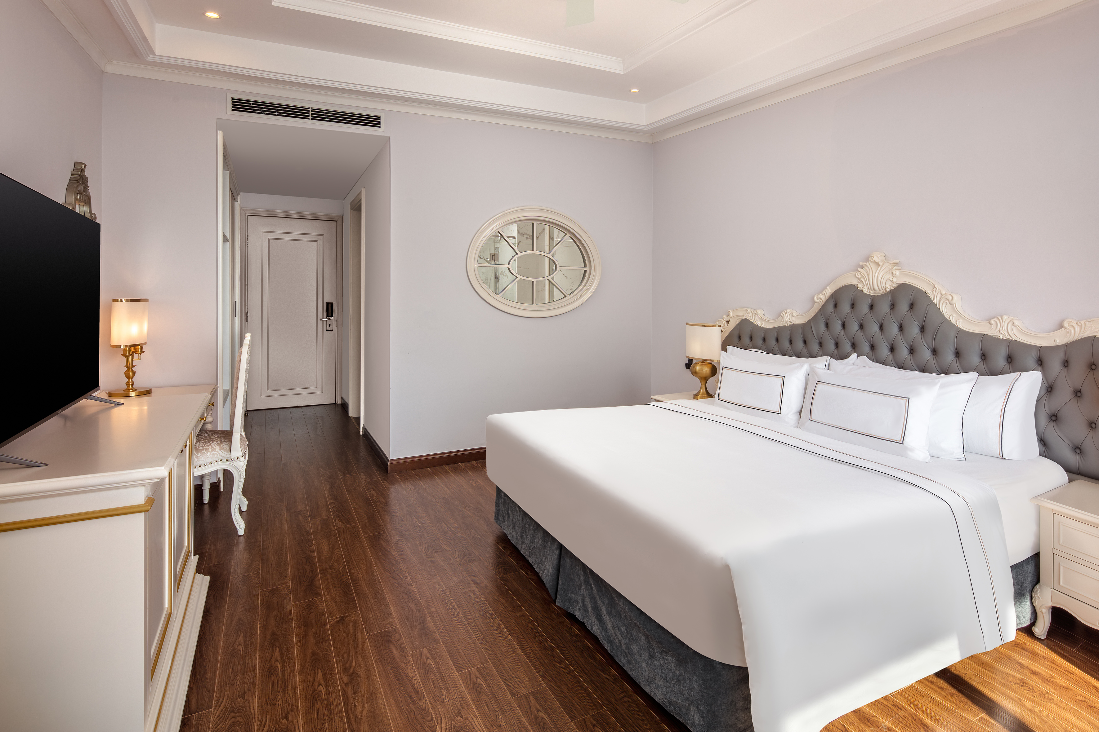 Luxurious hotel room featuring a king bed, tufted headboard, and wood floor.