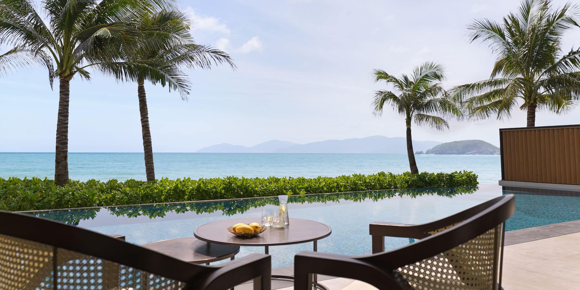 a table and chairs with a view of the ocean and palm trees