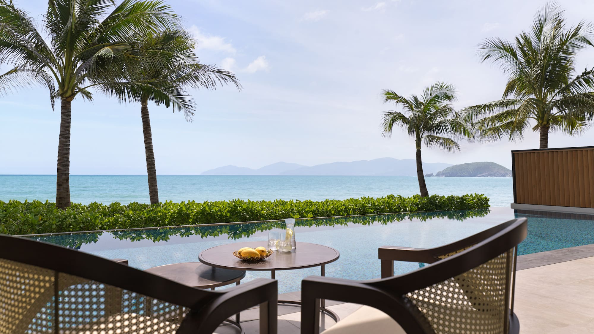 a table and chairs with a view of the ocean and palm trees