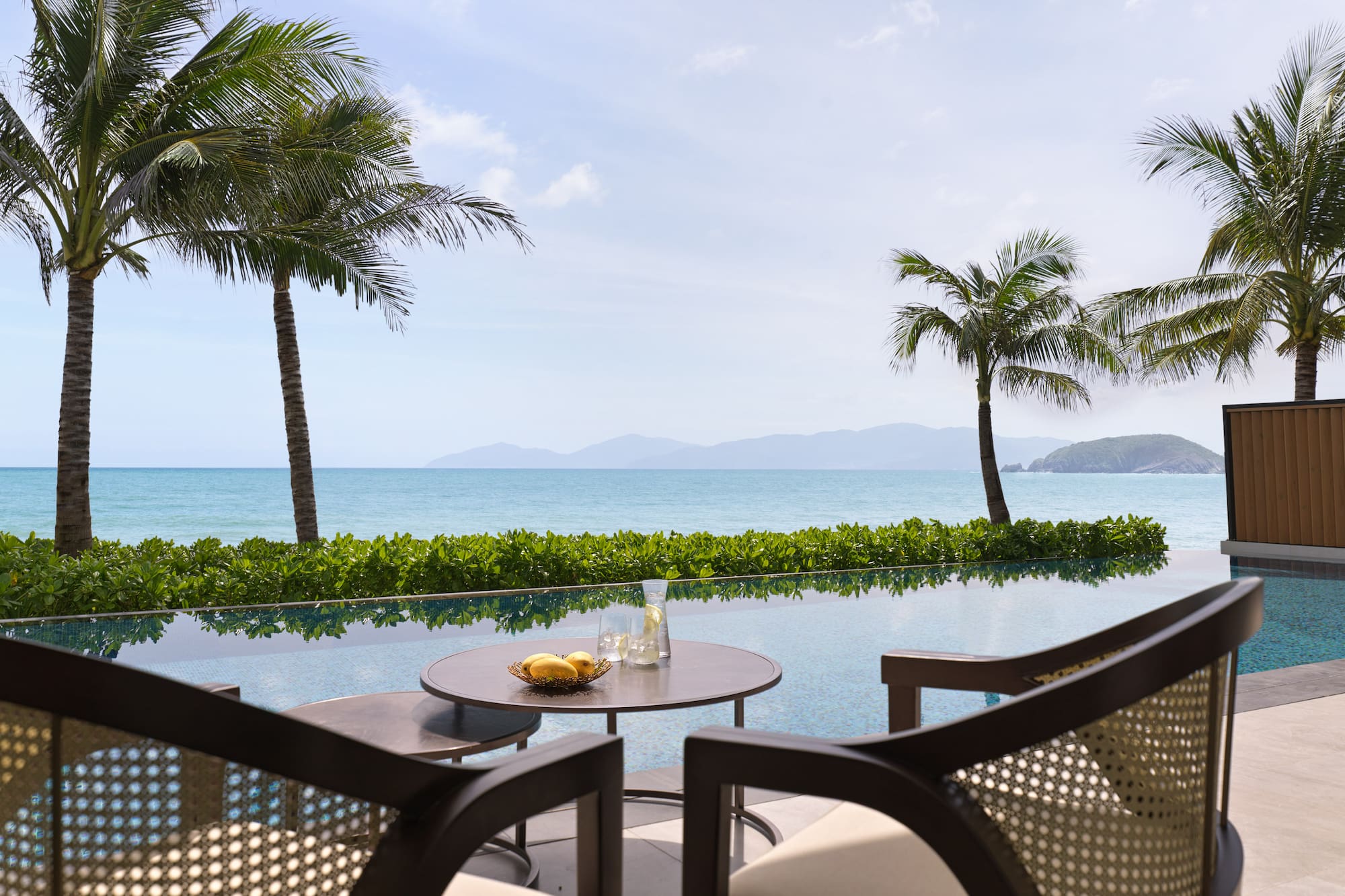 a table and chairs with a view of the ocean and palm trees