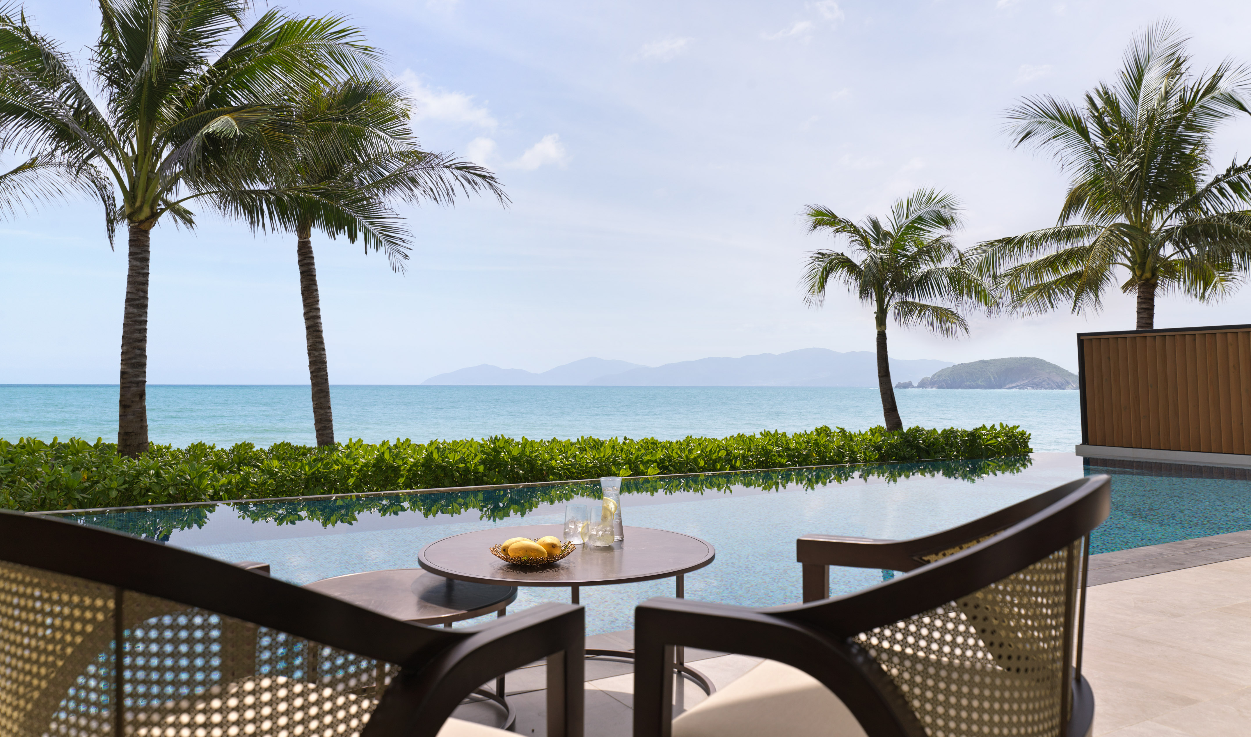 a table and chairs with a view of the ocean and palm trees