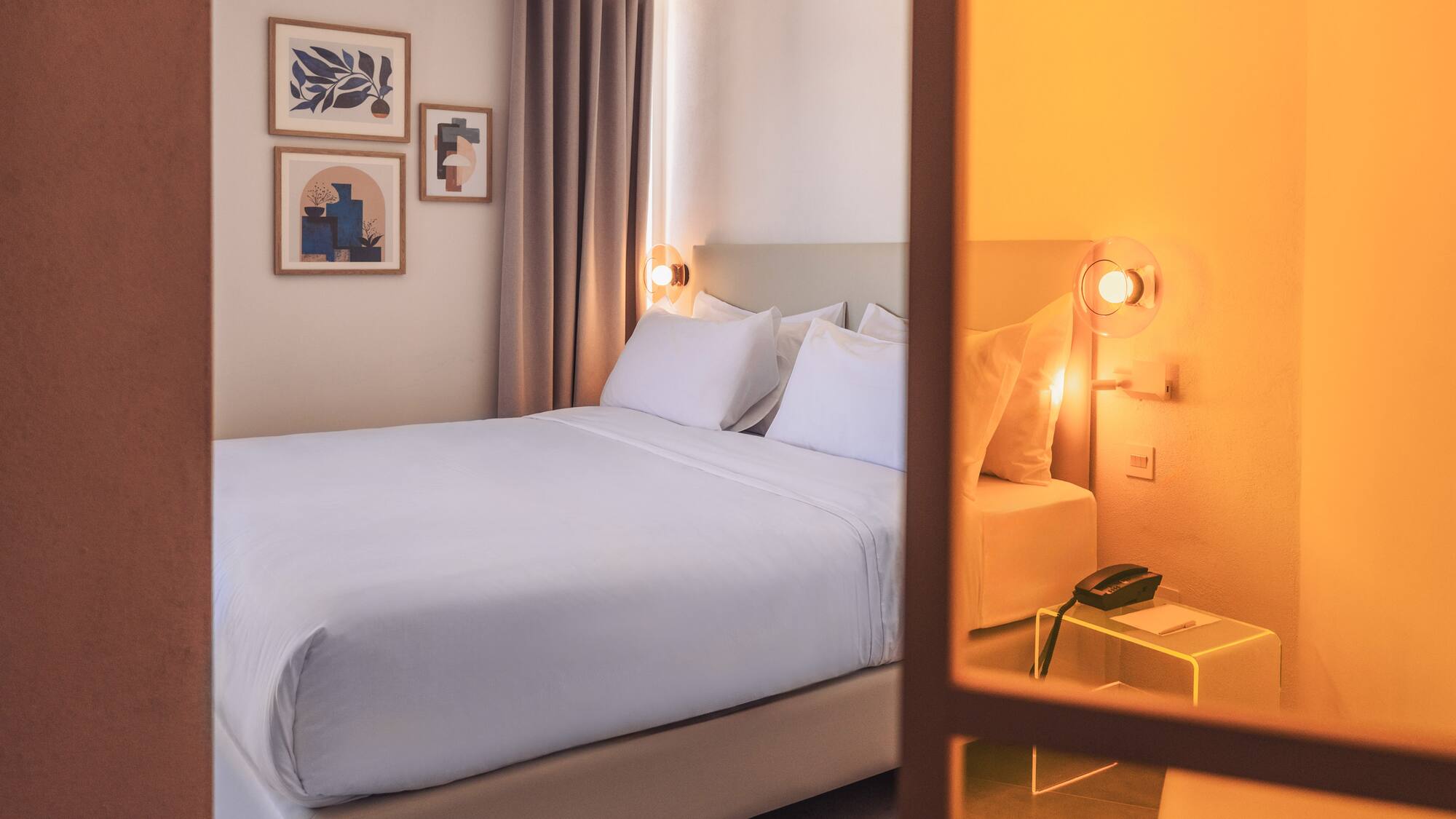 a bed with white sheets and pillows in a room