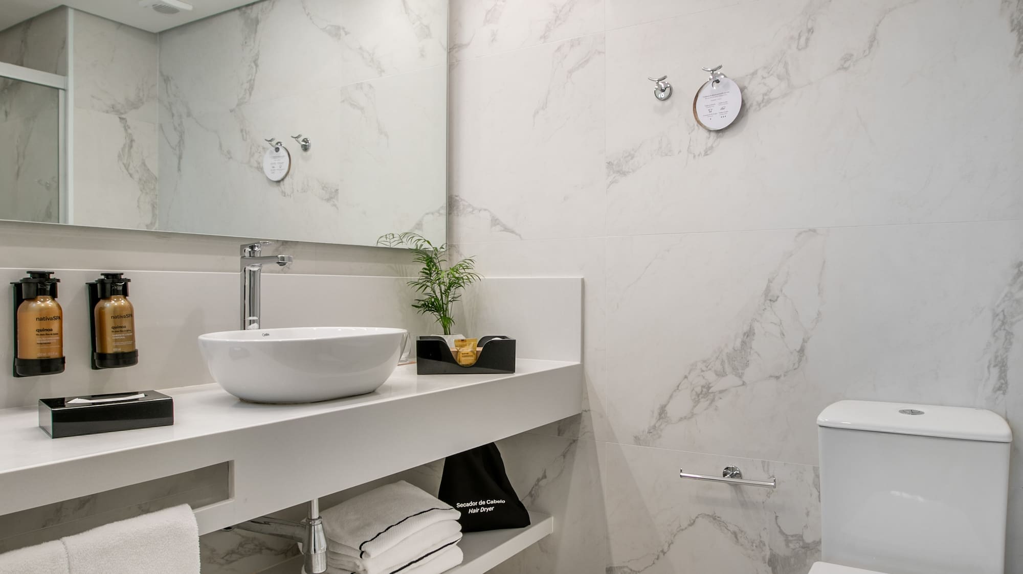 Sleek bathroom with white marble, floating vanity, vessel sink, and toilet.
