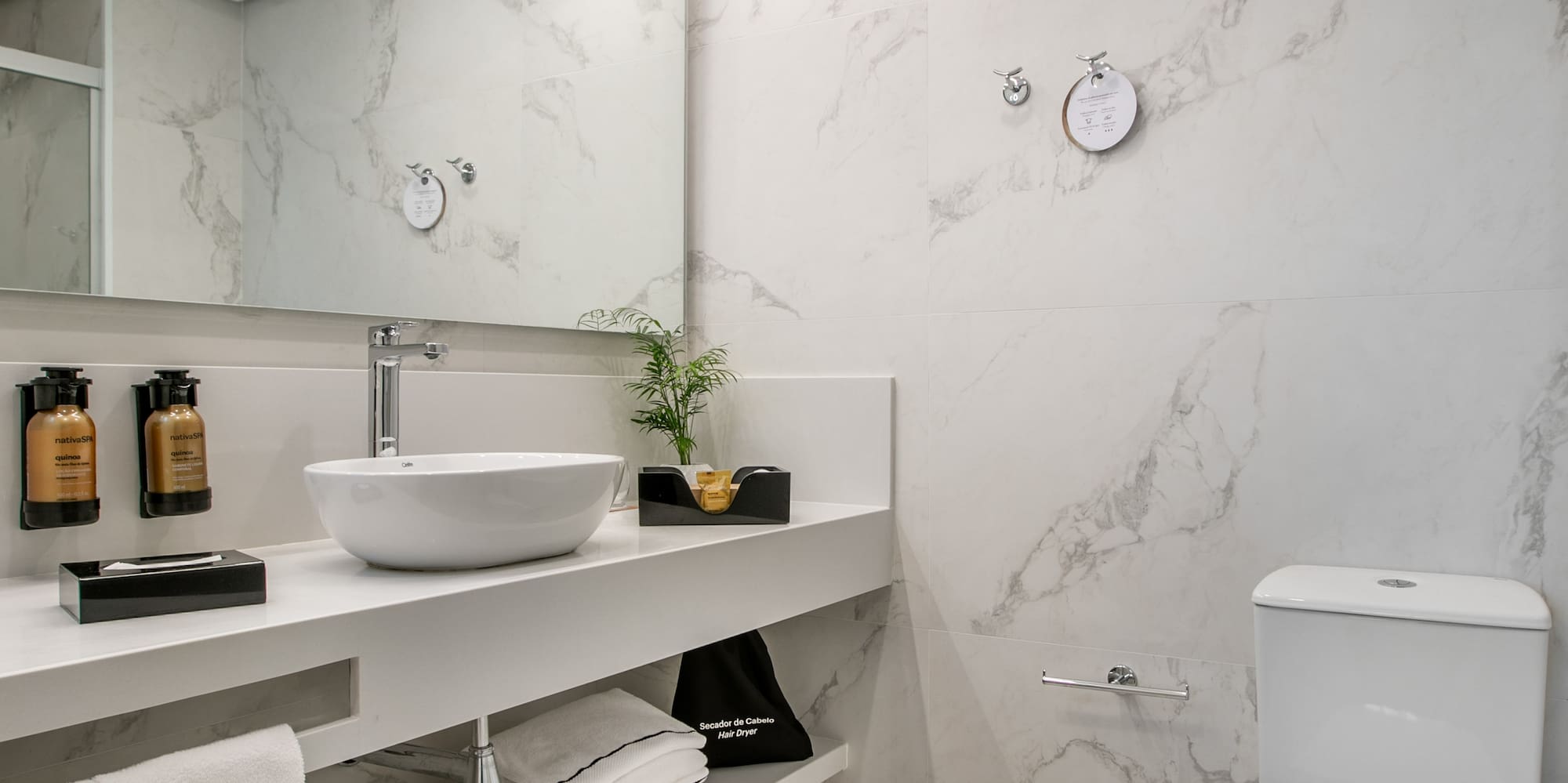 Sleek bathroom with white marble, floating vanity, vessel sink, and toilet.