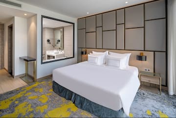 a bed with white sheets and a mirror in a room