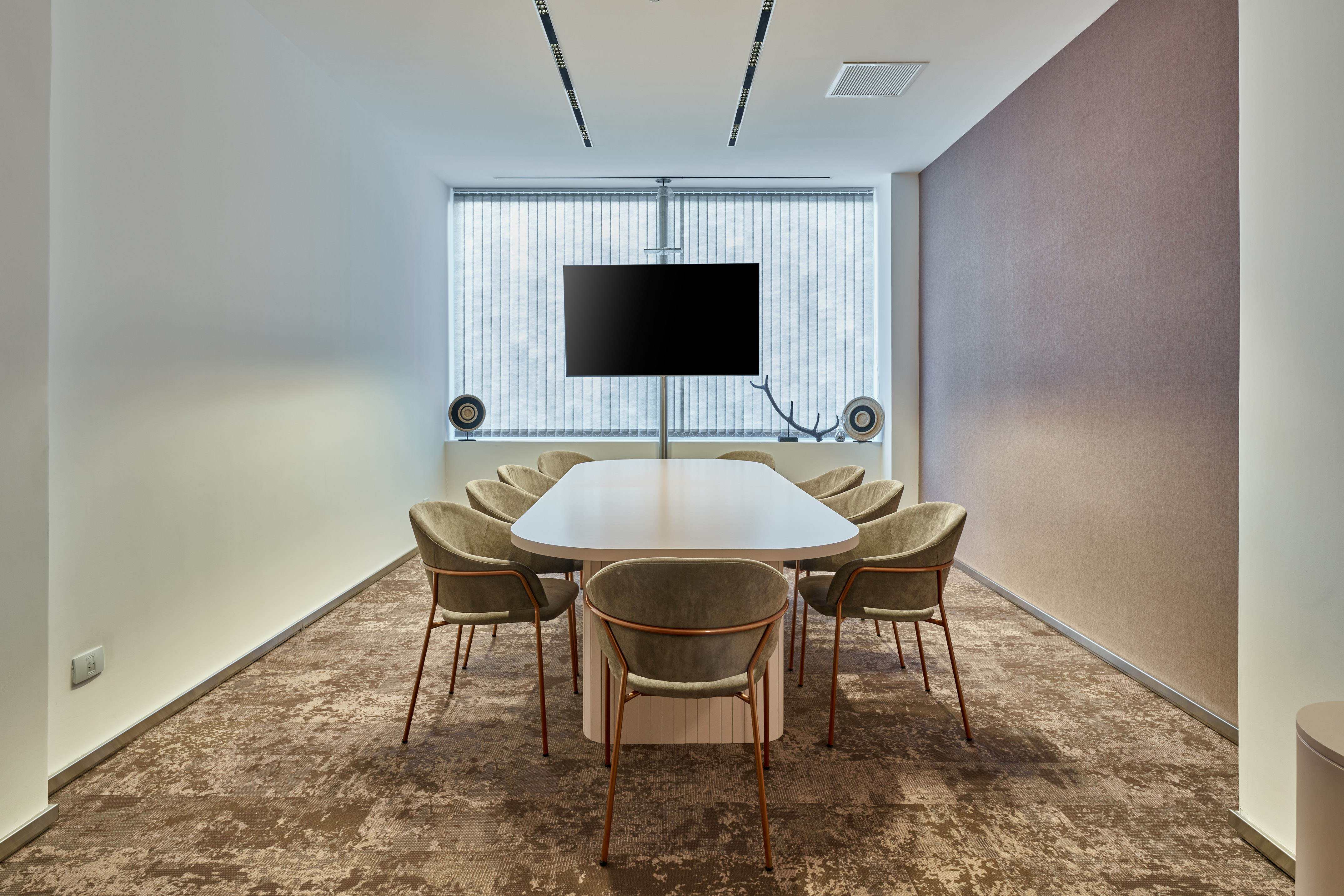Modern meeting room with conference table, chairs, and large TV screen.