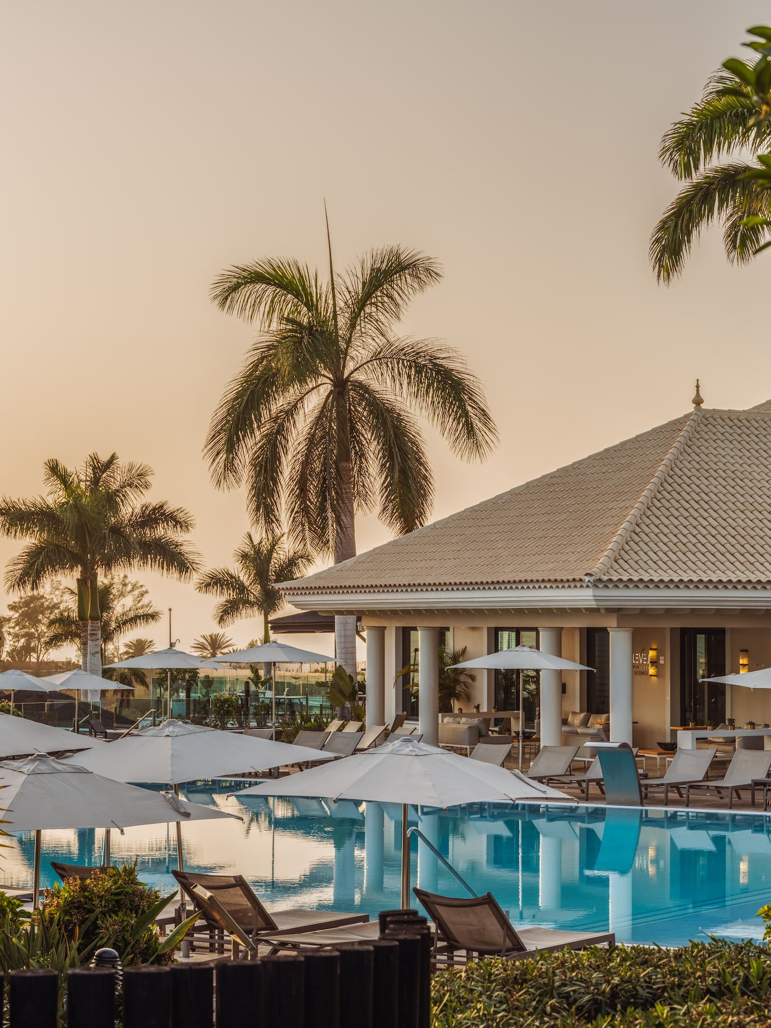 a pool with umbrellas and chairs in front of a building