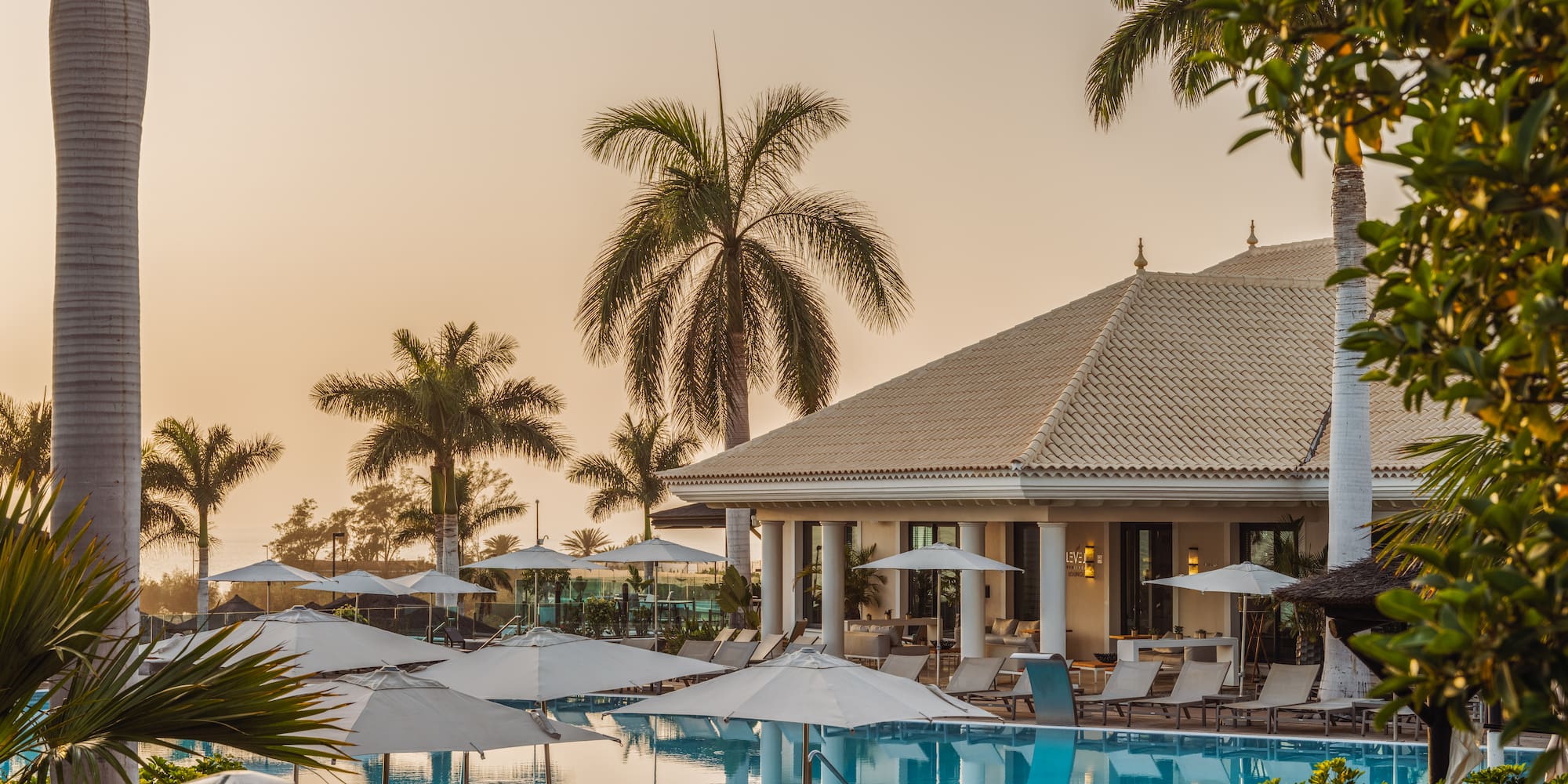 a pool with umbrellas and chairs in front of a building