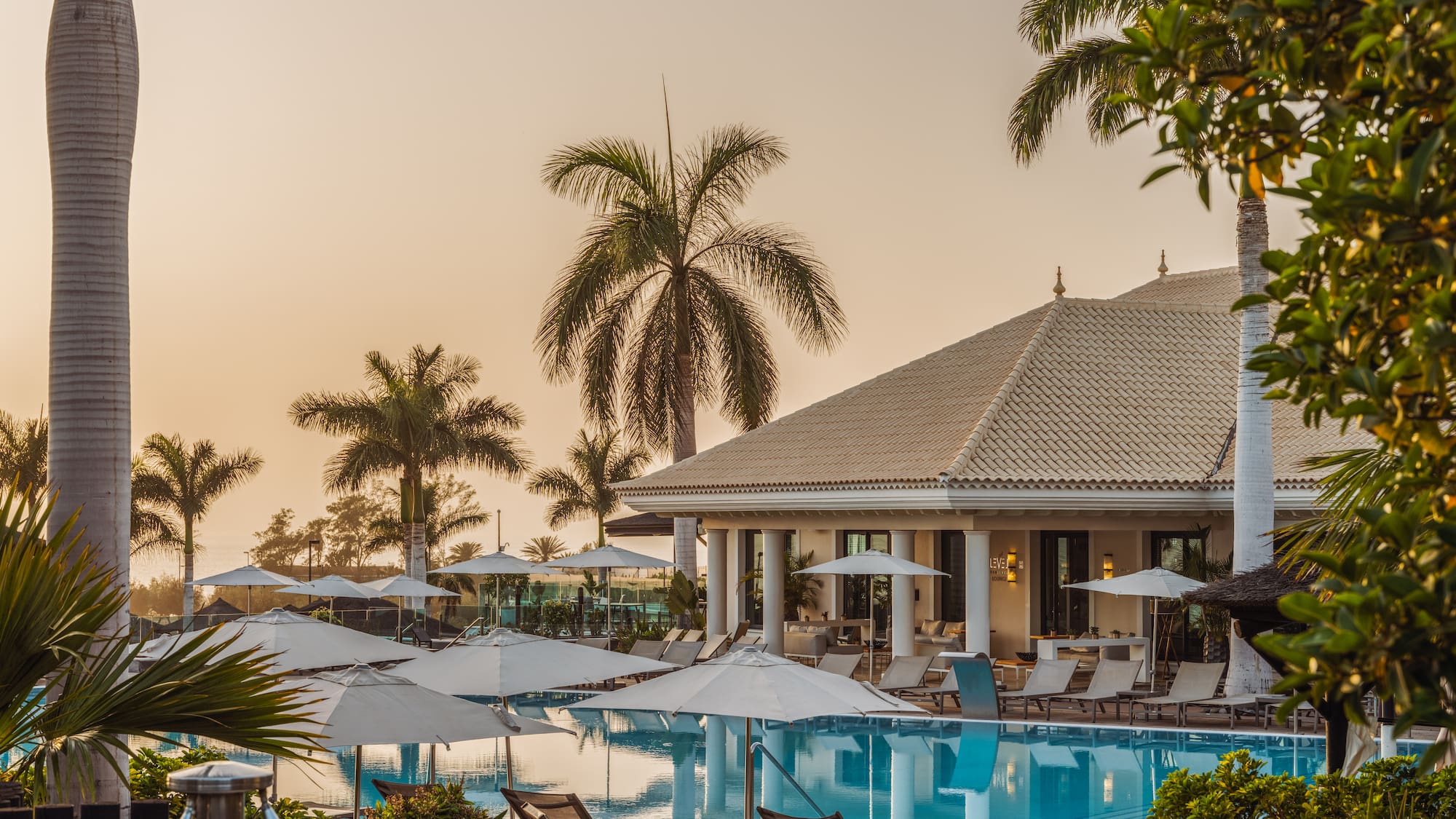 a pool with umbrellas and chairs in front of a building