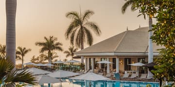 a pool with umbrellas and chairs in front of a building