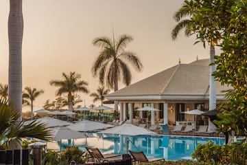 a pool with umbrellas and chairs in front of a building