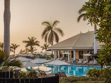 a pool with umbrellas and chairs in front of a building