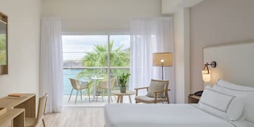 a room with a view of the ocean and a table and chairs