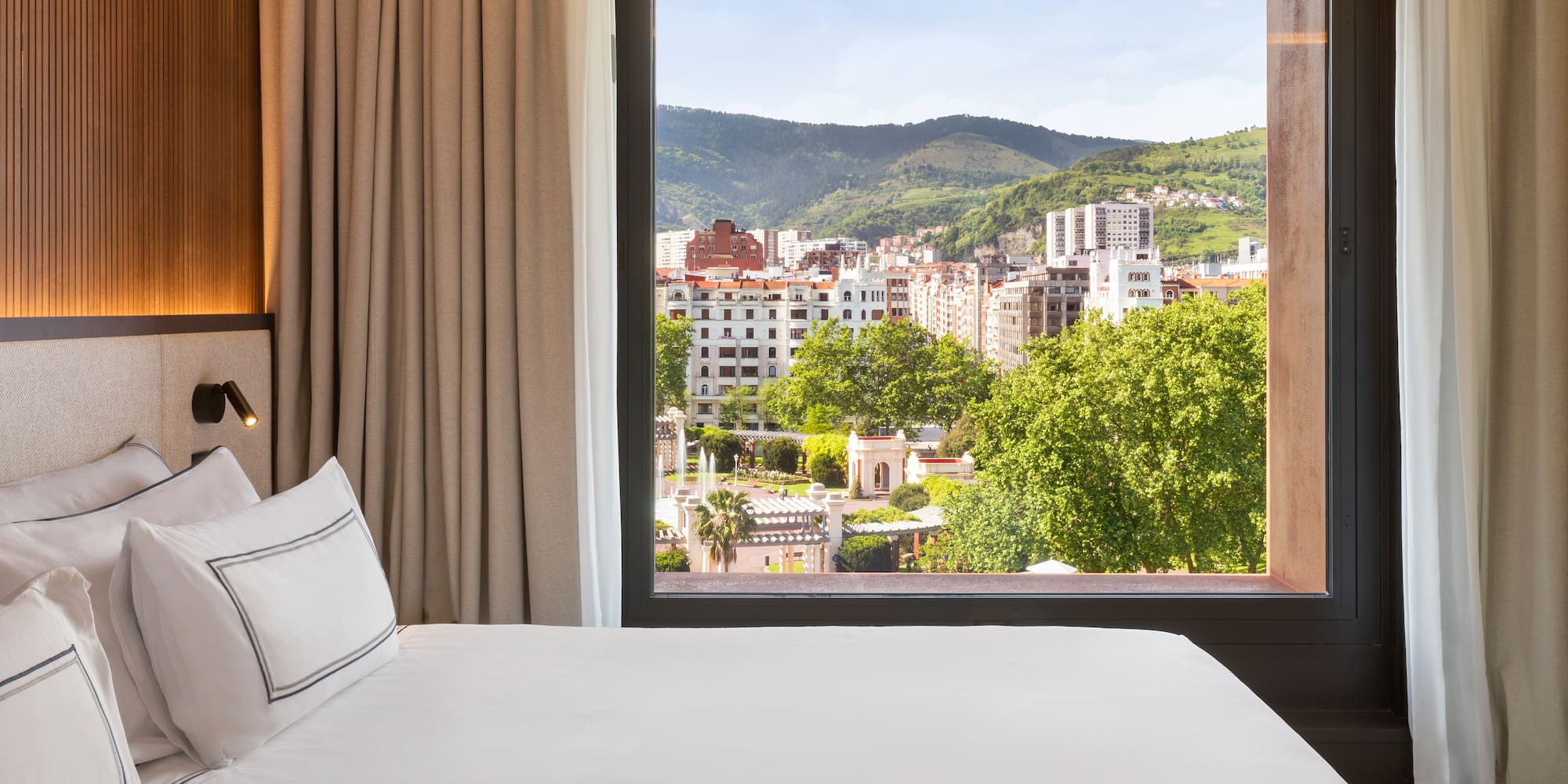 a bed with a view of a city from a window