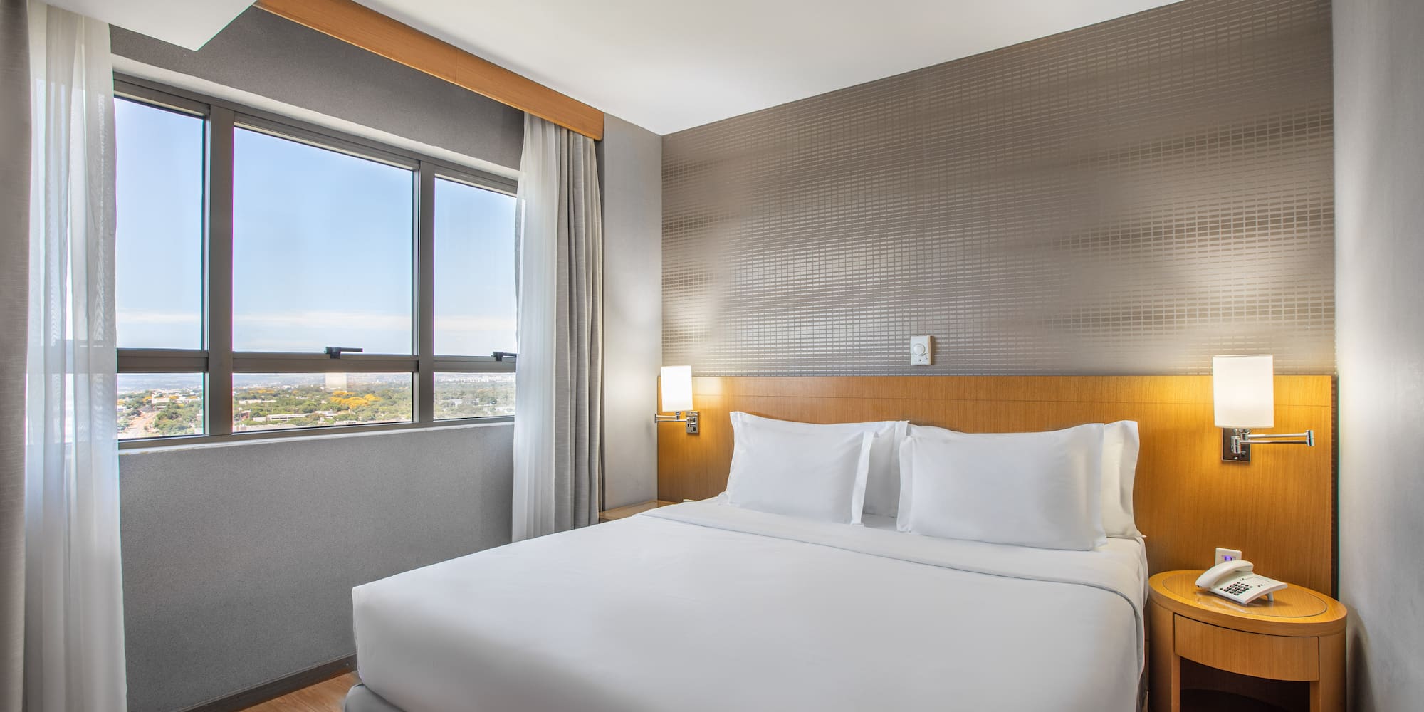 a bed with white sheets and a table in a room with a window