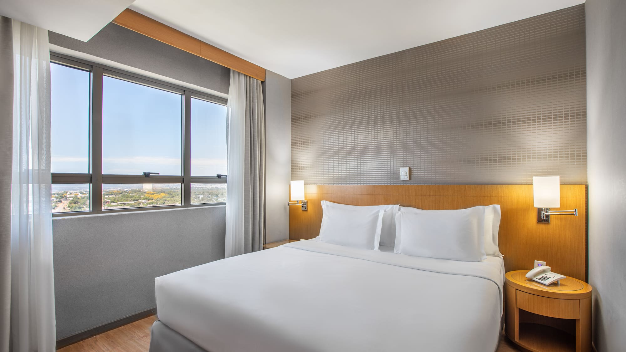 a bed with white sheets and a table in a room with a window