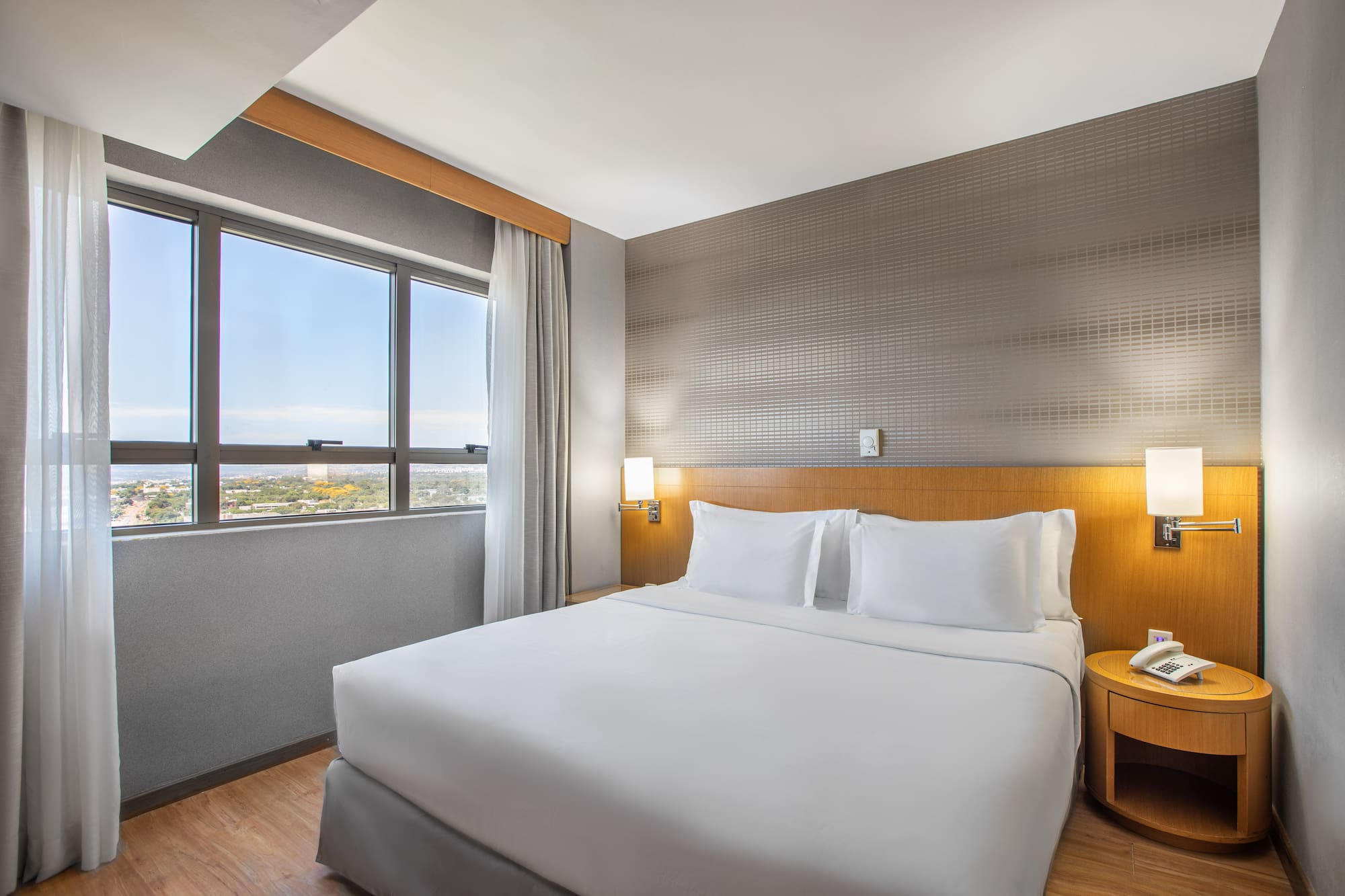 a bed with white sheets and a table in a room with a window