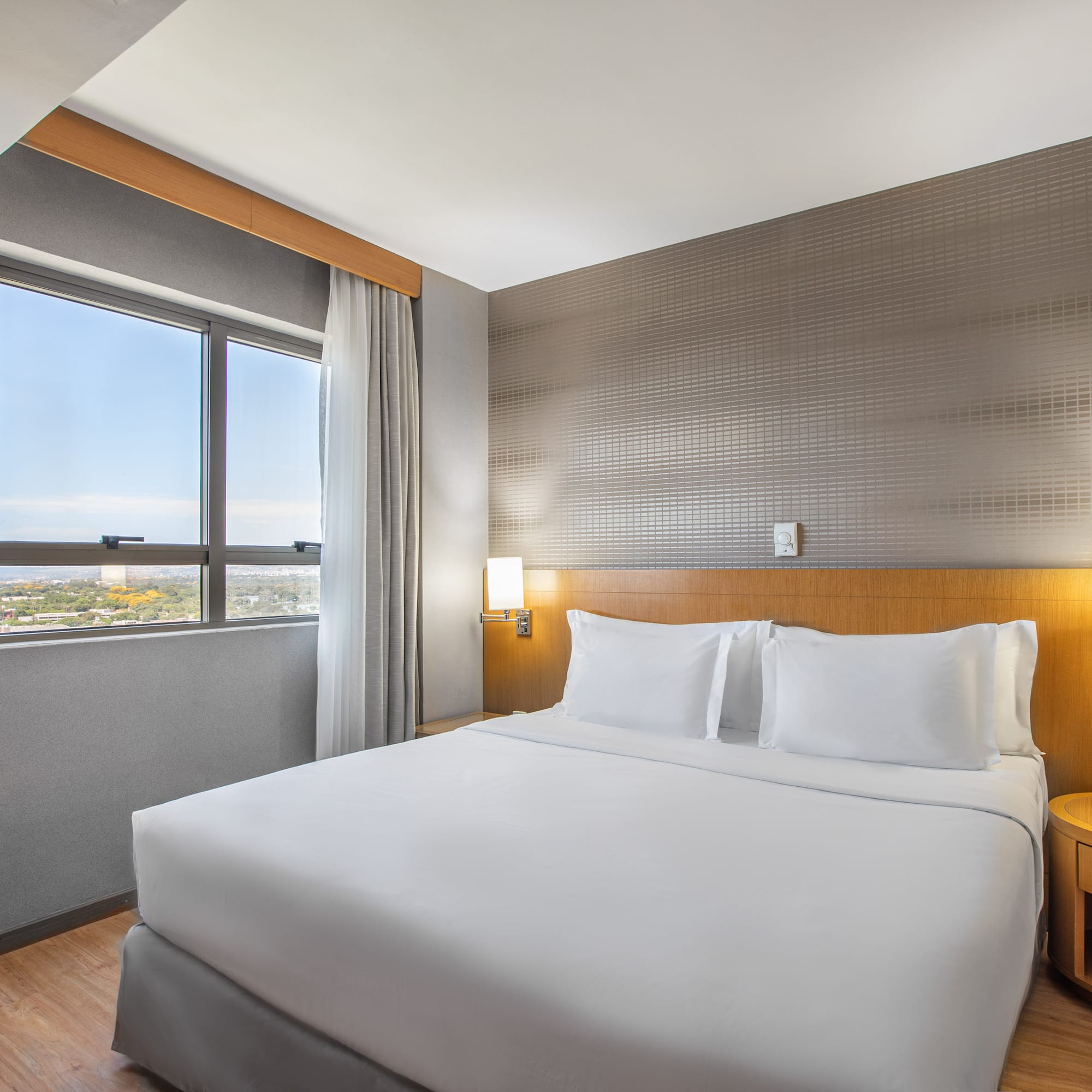 a bed with white sheets and a table in a room with a window