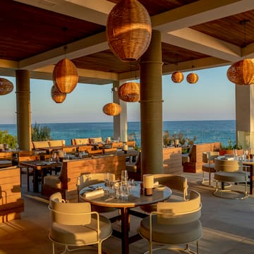 a restaurant with tables and chairs and a view of the ocean