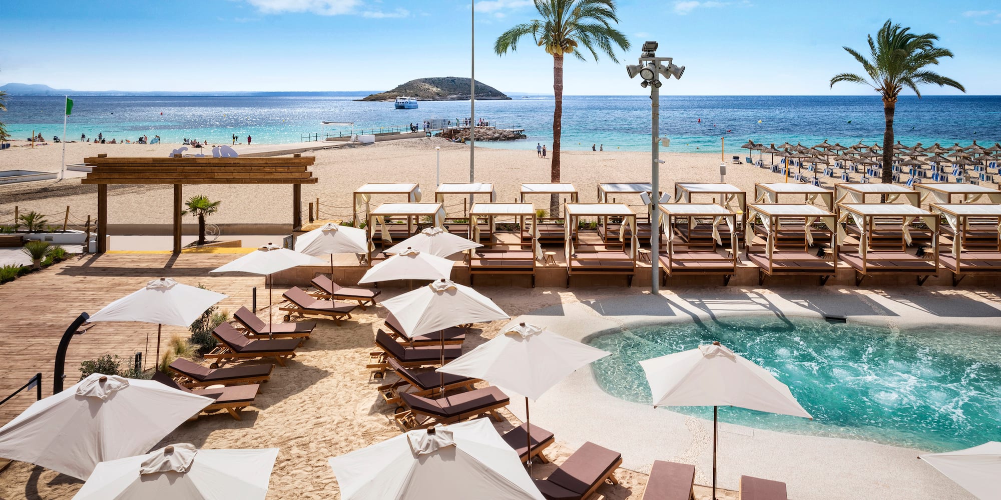 a beach with umbrellas and chairs and a pool
