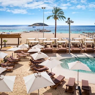 a beach with umbrellas and chairs and a pool