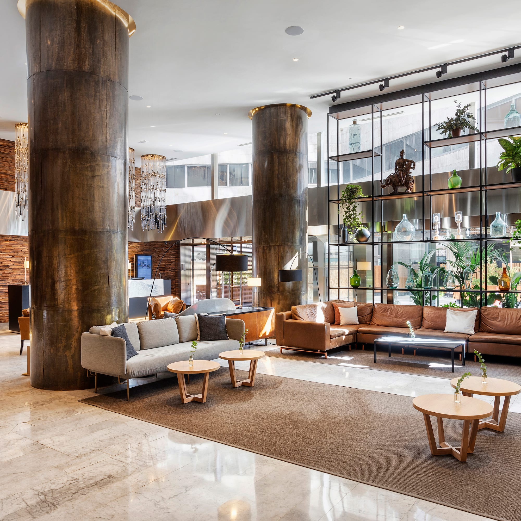 Modern hotel lobby with chandeliers, comfortable seating, and a reception desk.