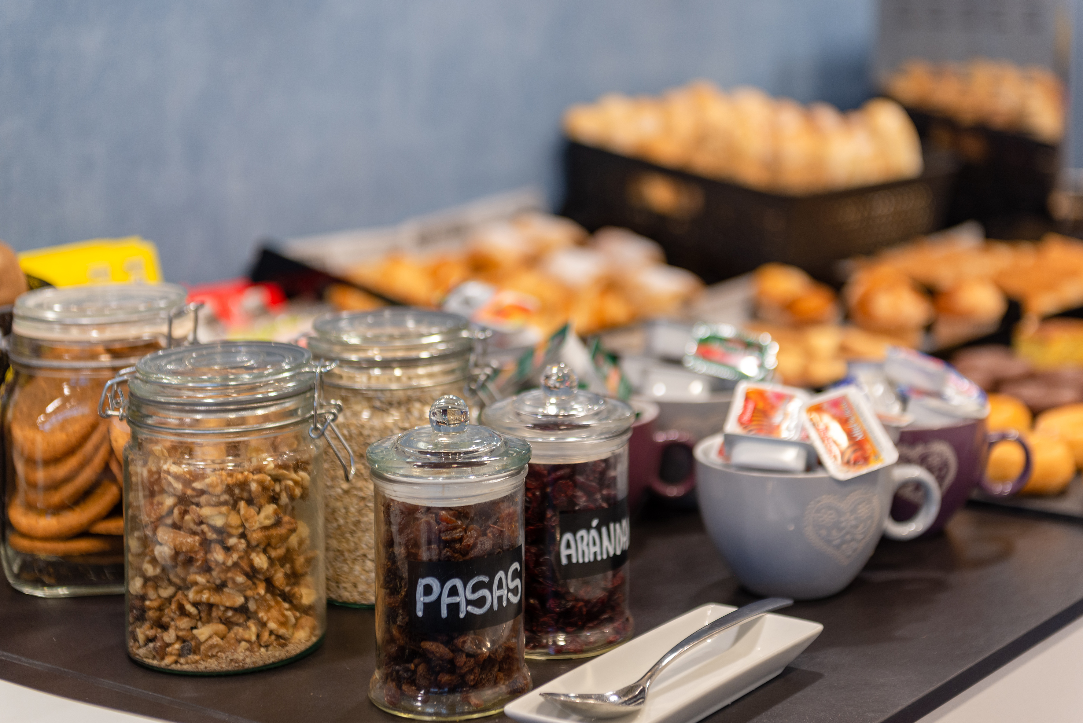 Breakfast buffet with nuts, dried fruits, oats, and assorted pastries.