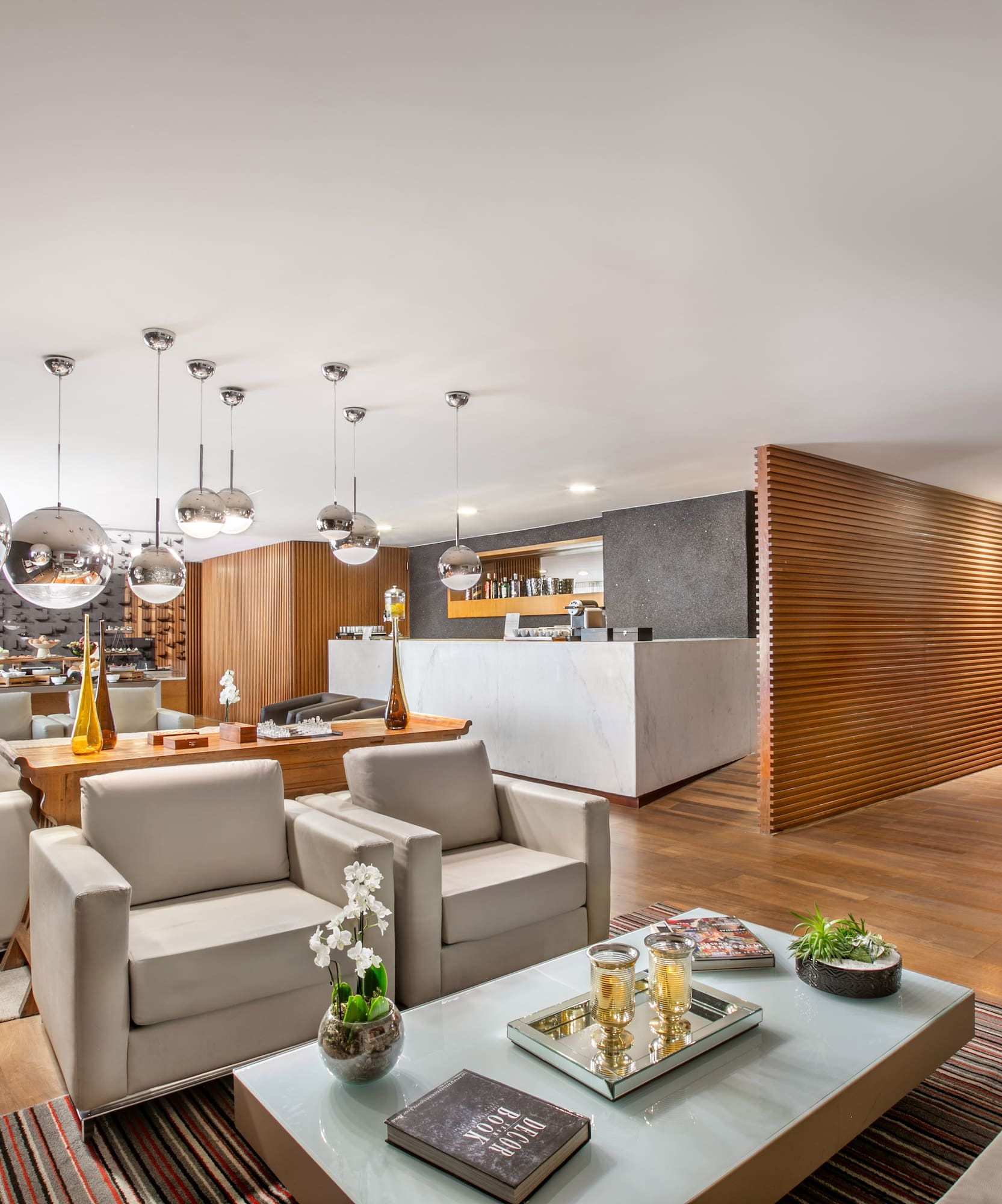 Modern hotel lounge with comfortable seating, marble bar, and wooden decor.