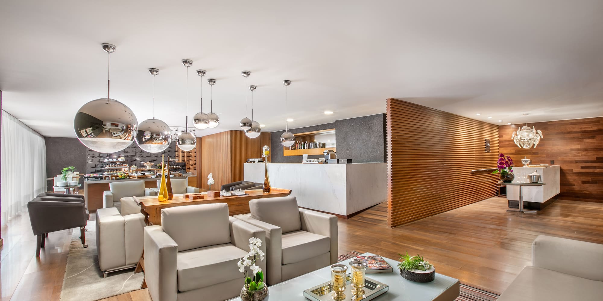 Modern hotel lounge with elegant seating, white bar, and warm wood accents.