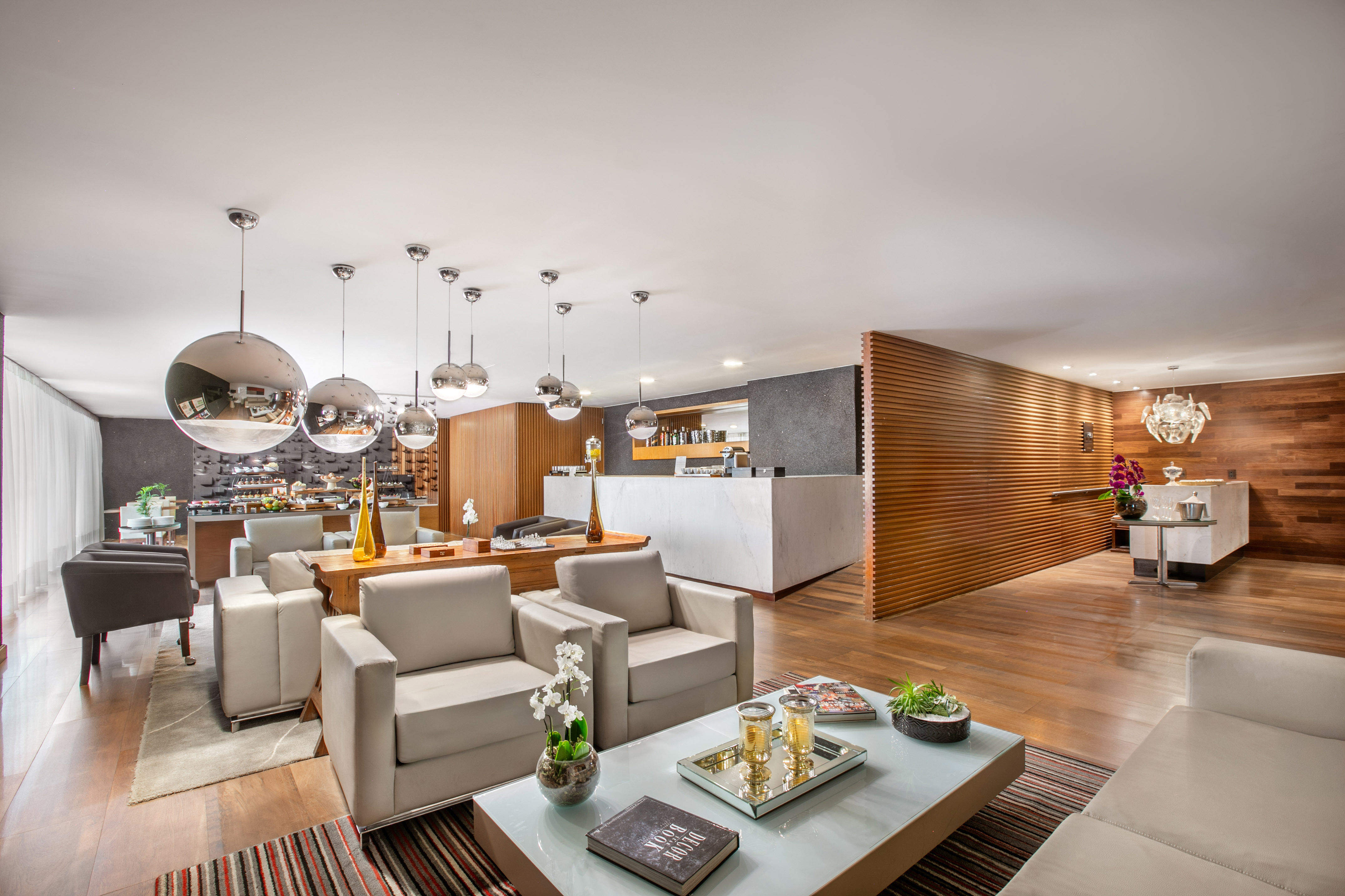 Modern hotel lounge with comfortable seating, spherical lights, and marble reception counter.