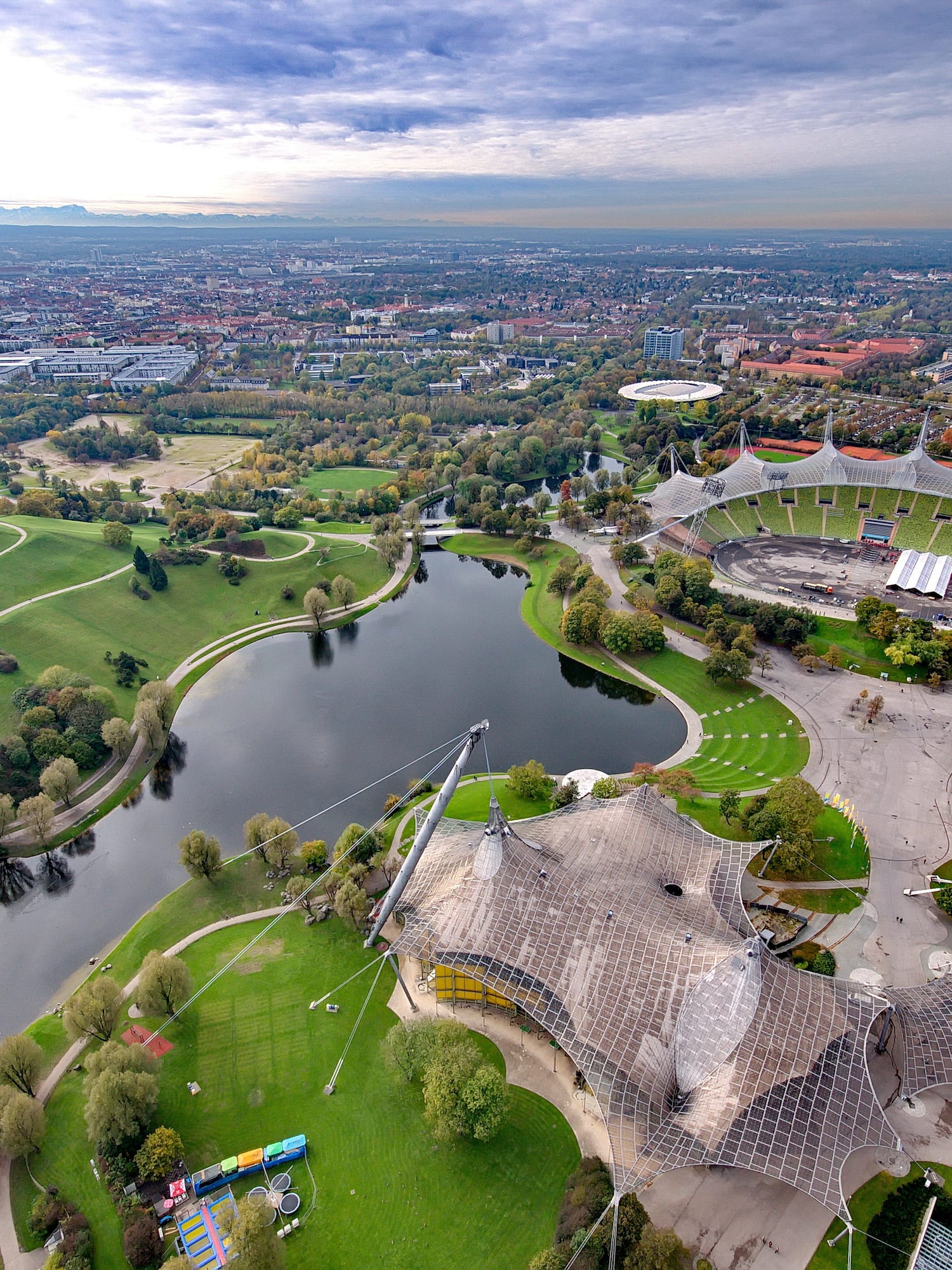 Vista aérea del Parque Olímpico de Múnich con estadio, lago y paisaje verde.