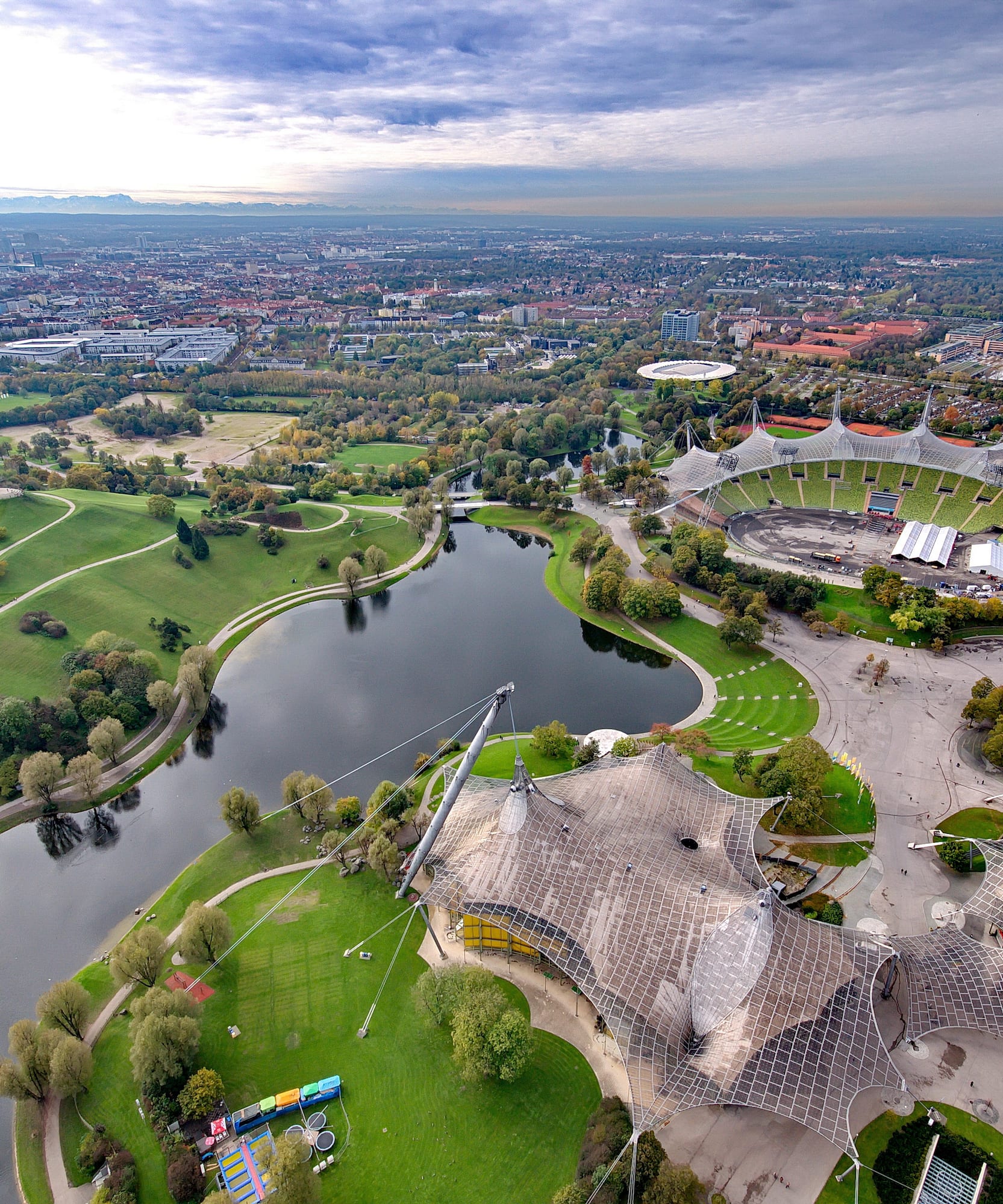 Vista aérea del Parque Olímpico de Múnich con estadio, lago y paisaje verde.