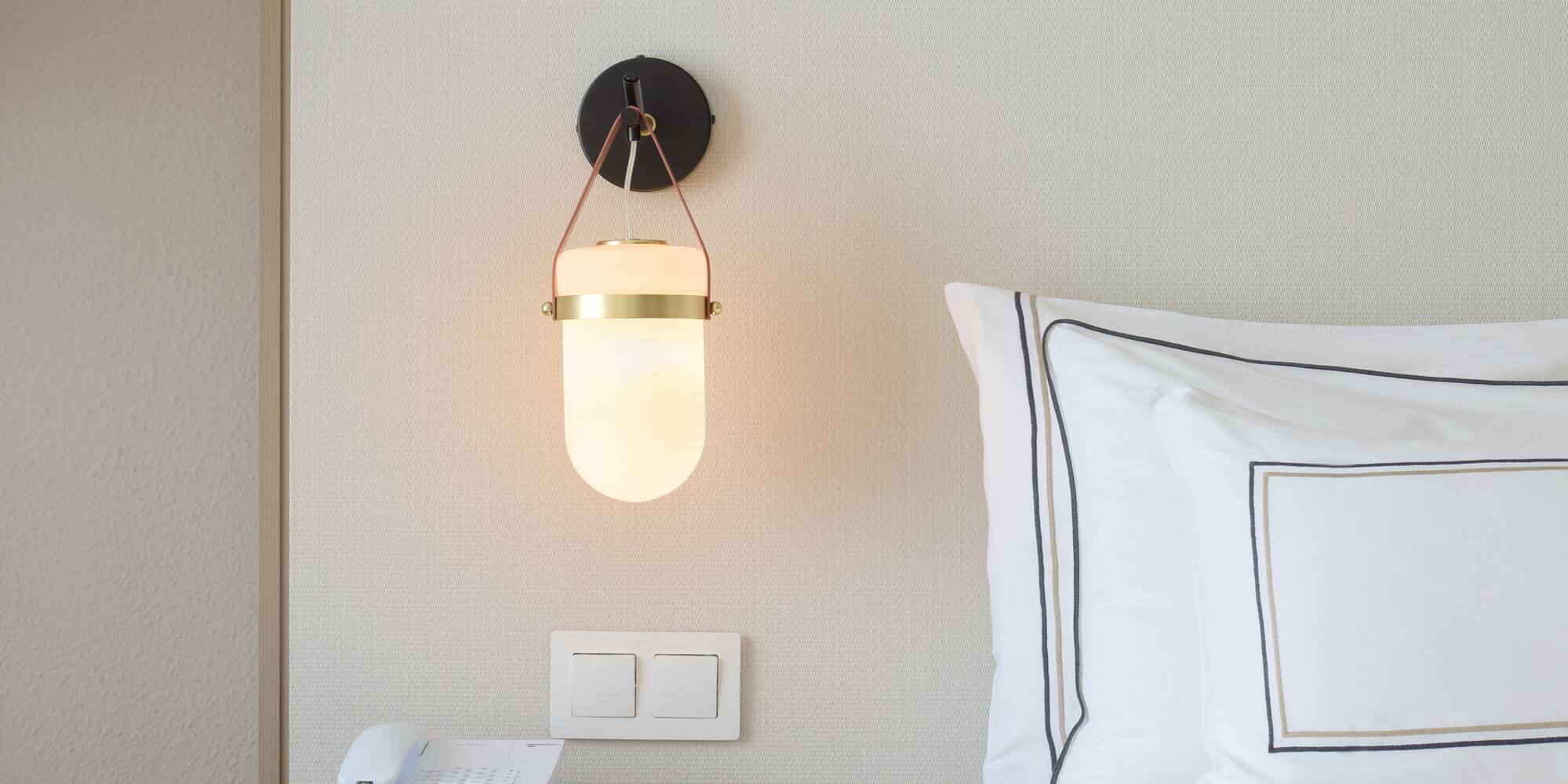 a bed with a phone and a lamp