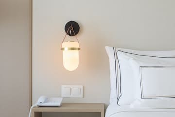 a bed with a phone and a lamp