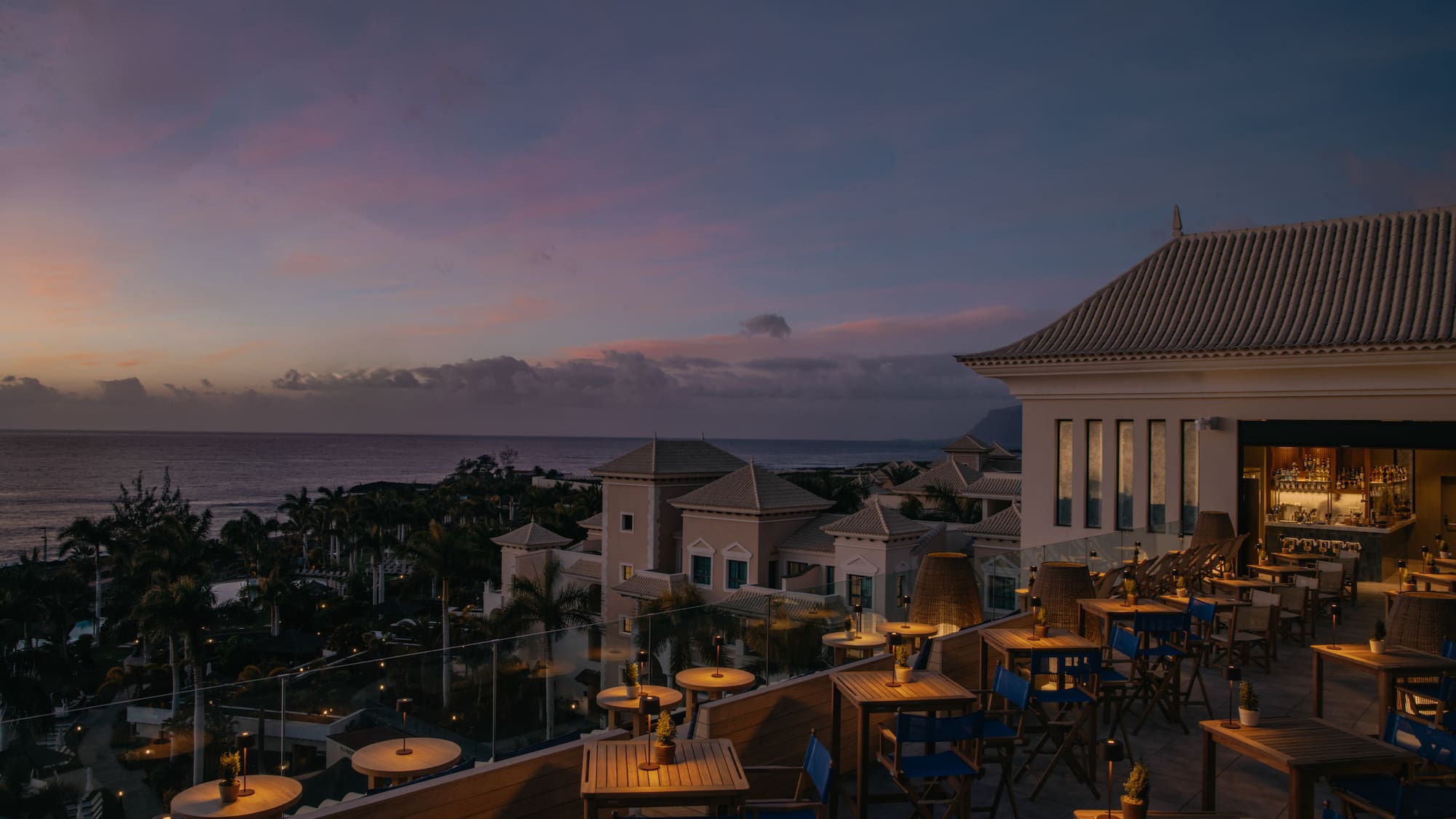 a rooftop restaurant with tables and chairs and a body of water