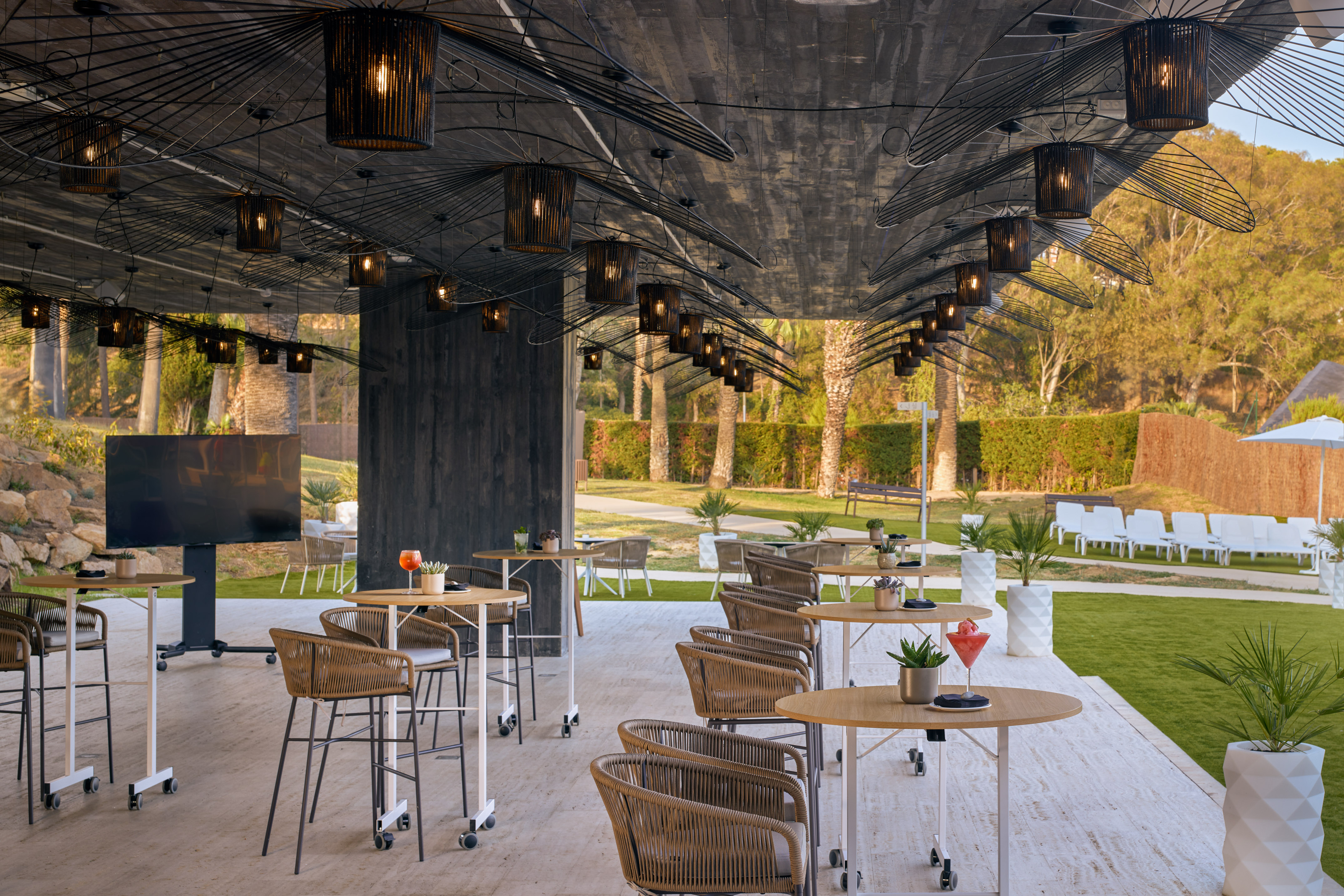 Modern outdoor bar patio with stylish seating and distinctive ceiling lights.