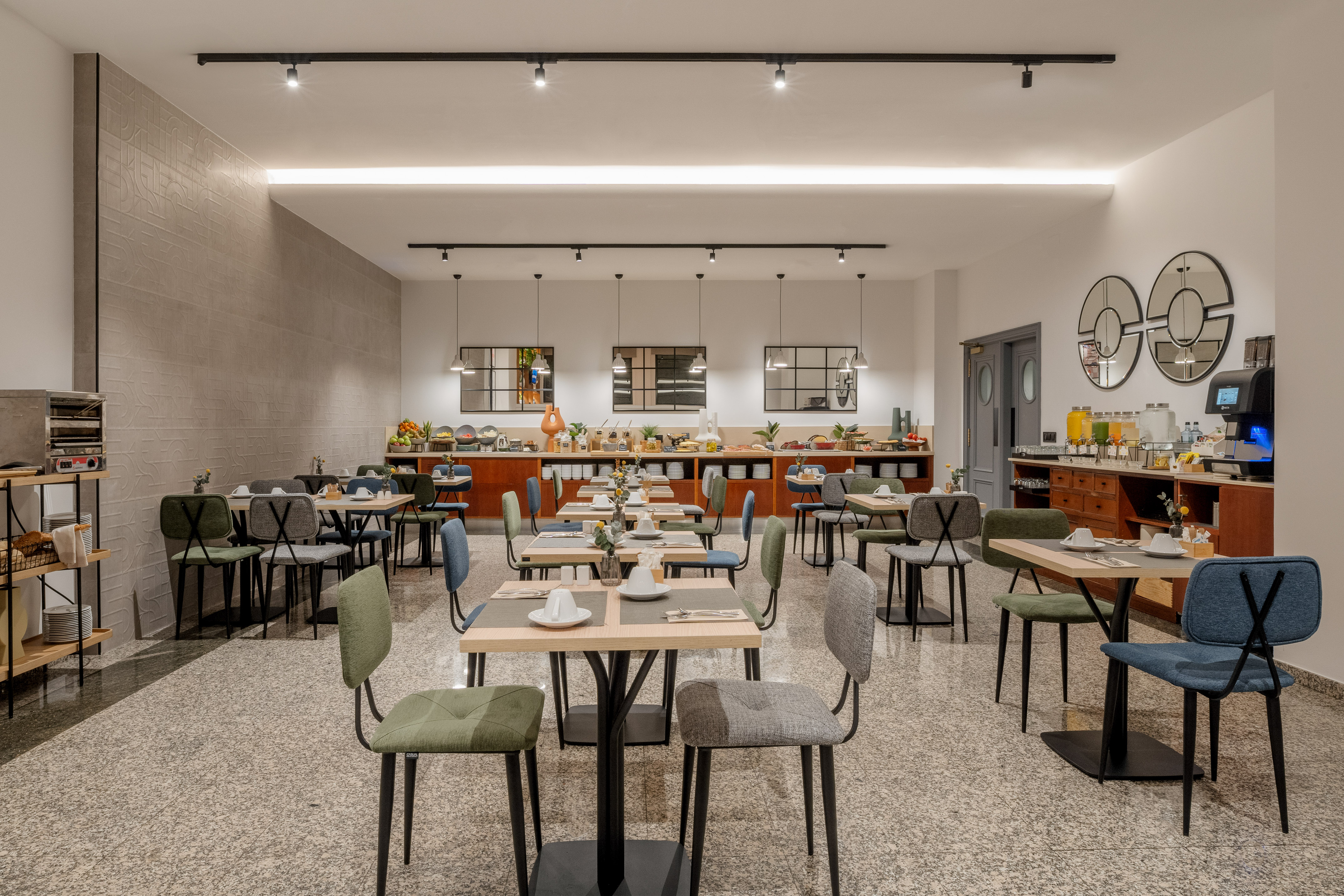 Modern hotel dining room with set tables and a breakfast buffet.