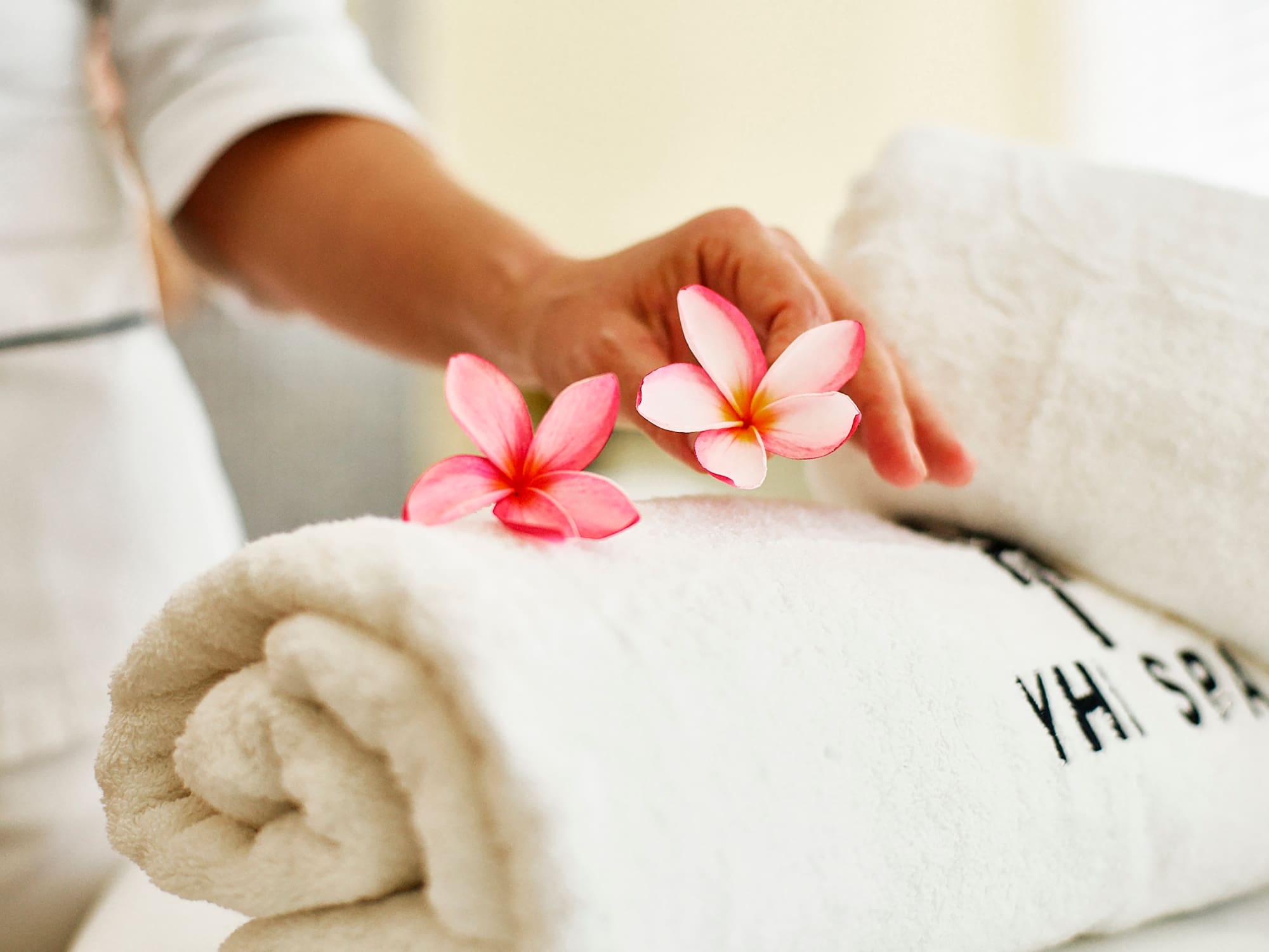 a person's hand holding flowers over a rolled up towel