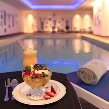 a bowl of fruit and a drink on a plate next to a pool