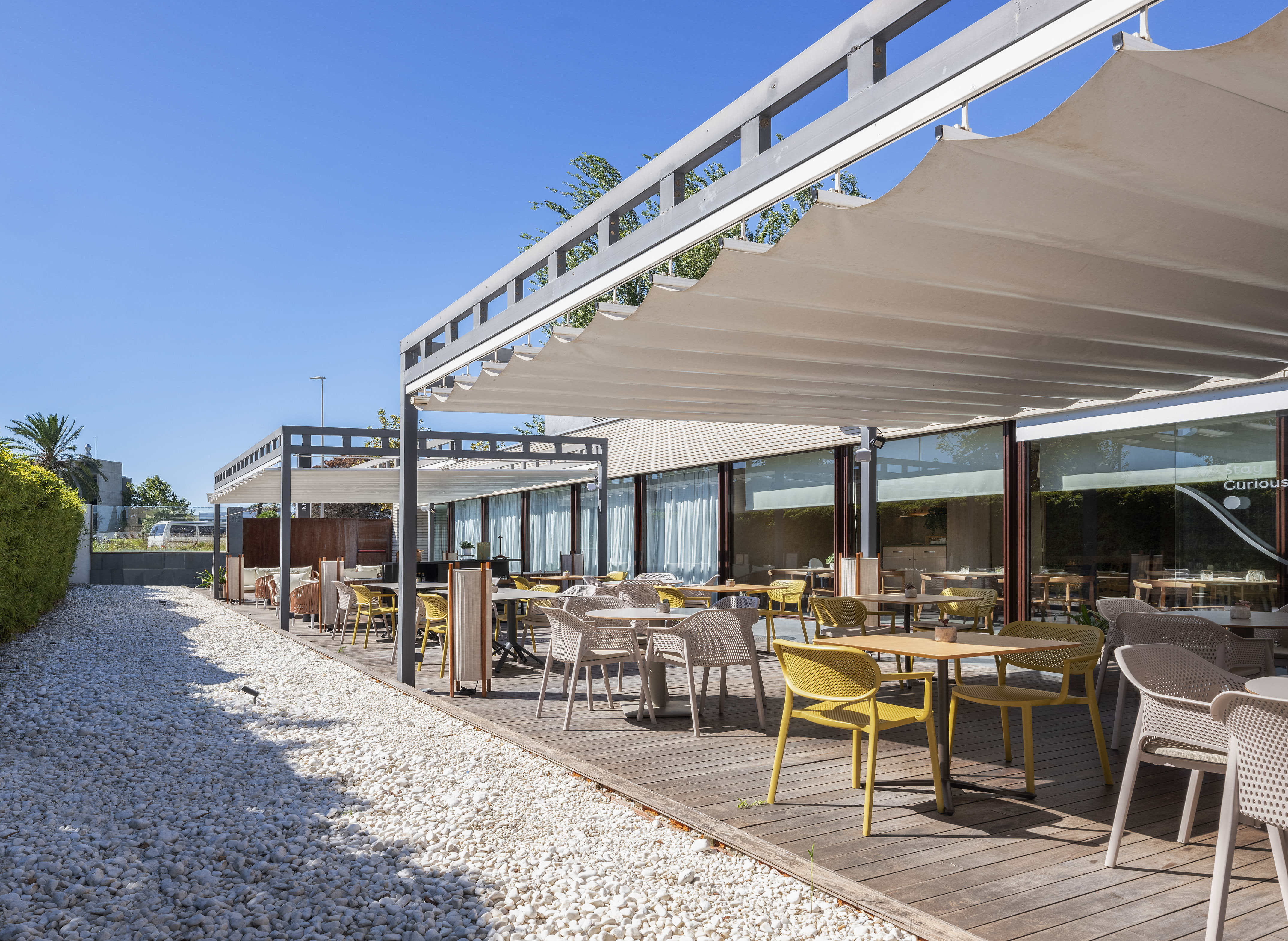 Outdoor dining patio with yellow chairs, wooden deck, and white retractable awning.